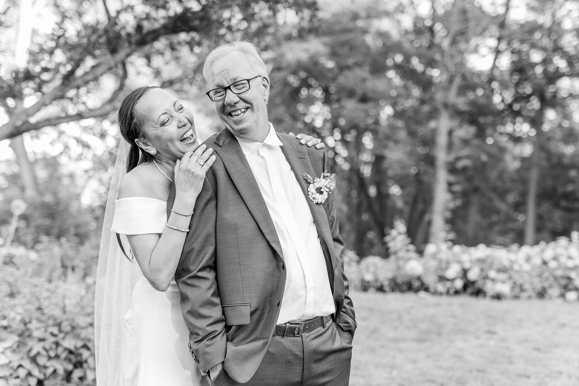 bride and groom laughing together surrounded by greenery