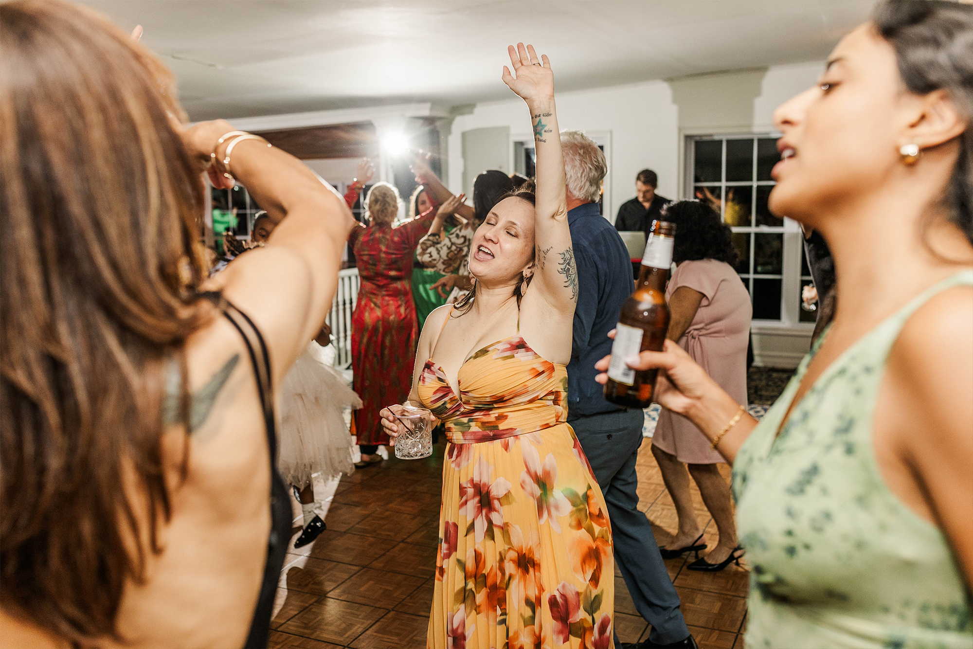 wedding guests with drinks in hand dancing on dance floor
