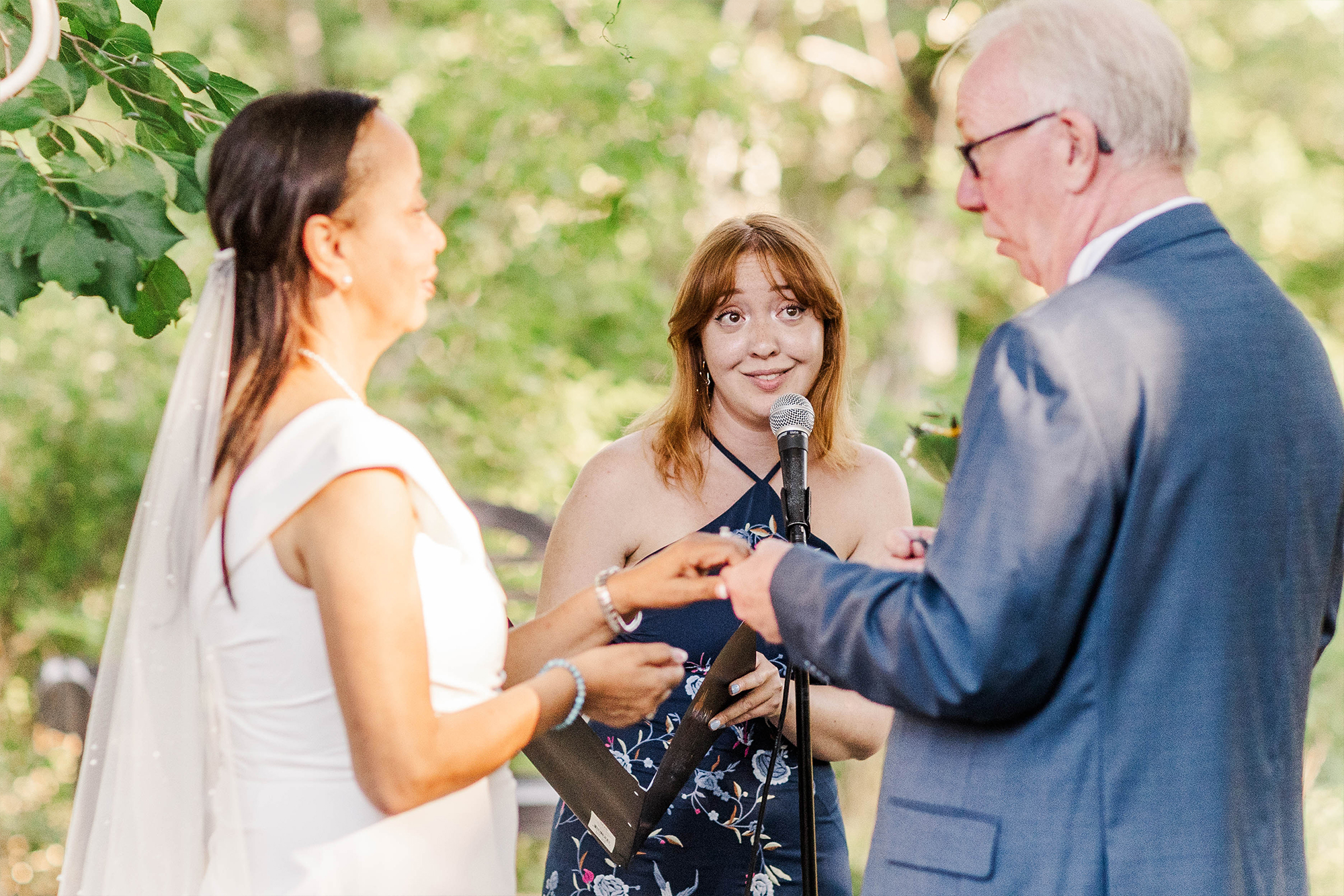 bride and groom with wedding officiant underneath wedding arch