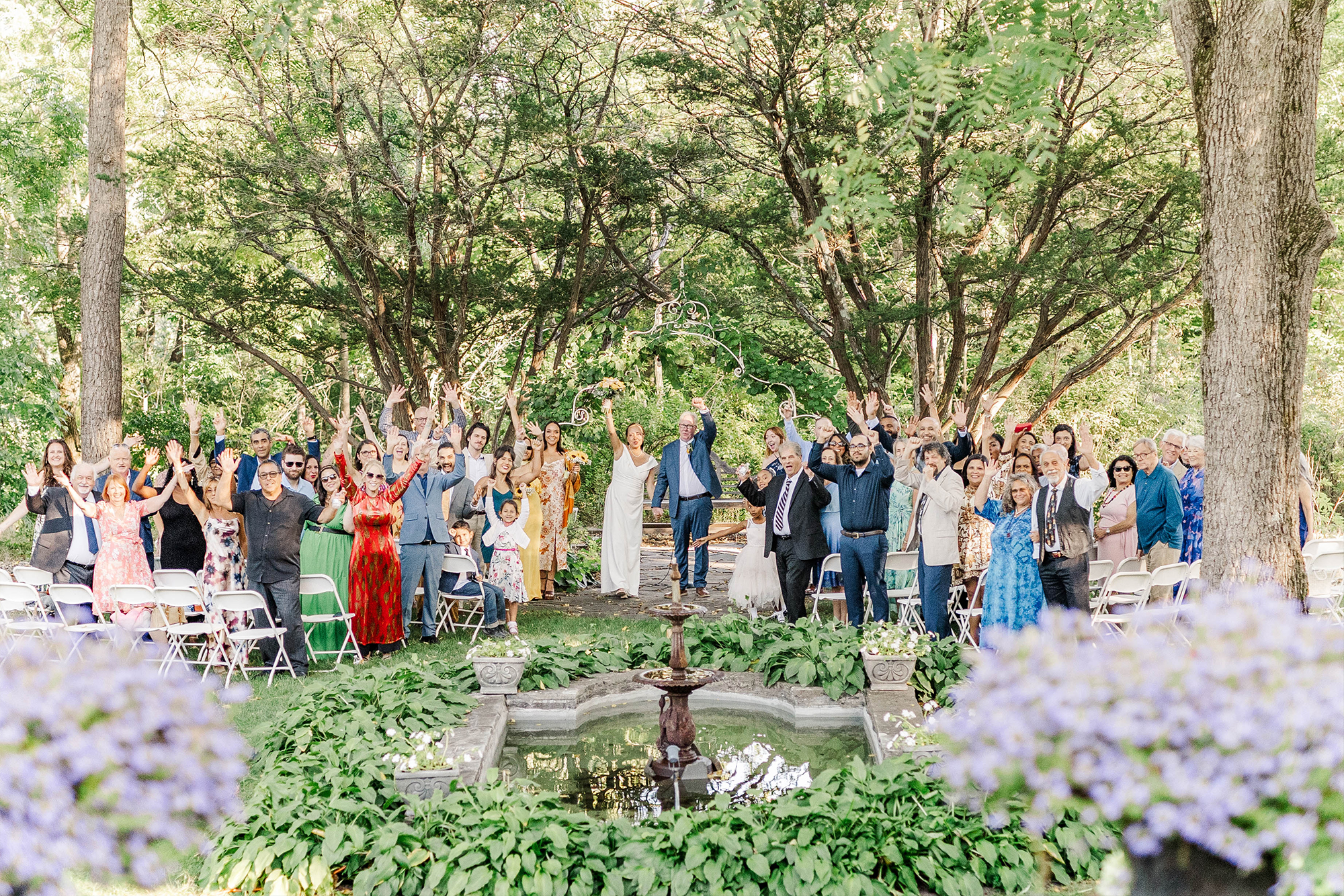 bride and groom cheer underneath wedding arch with cheering wedding guests surrounded by ceremony space