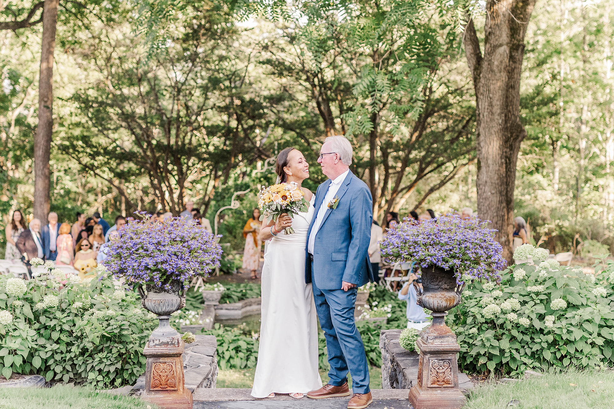 bride and groom sharing a moment at top of stone stairs in front of wedding ceremony space
