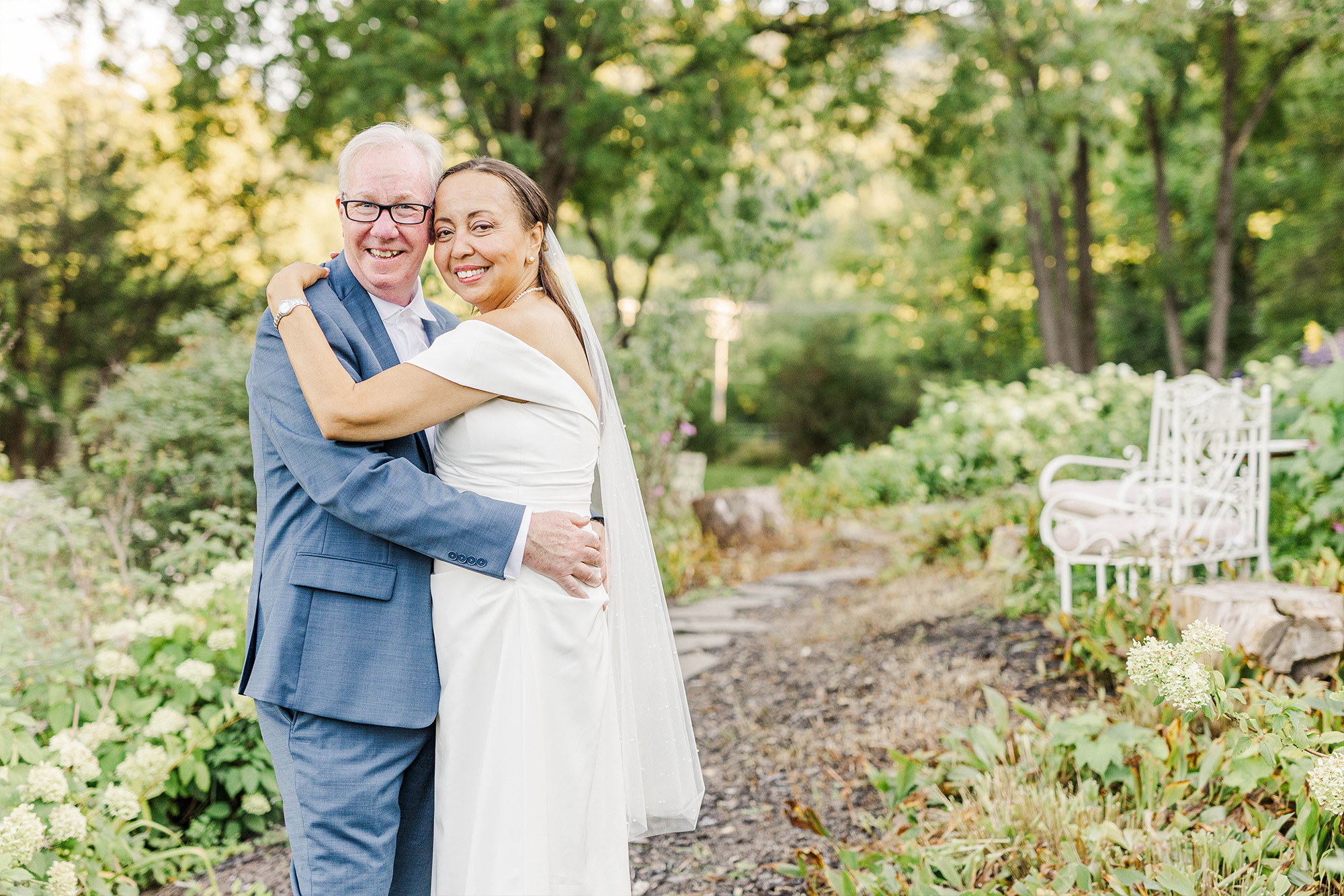 bride and groom posing with each other on stone path with greenery