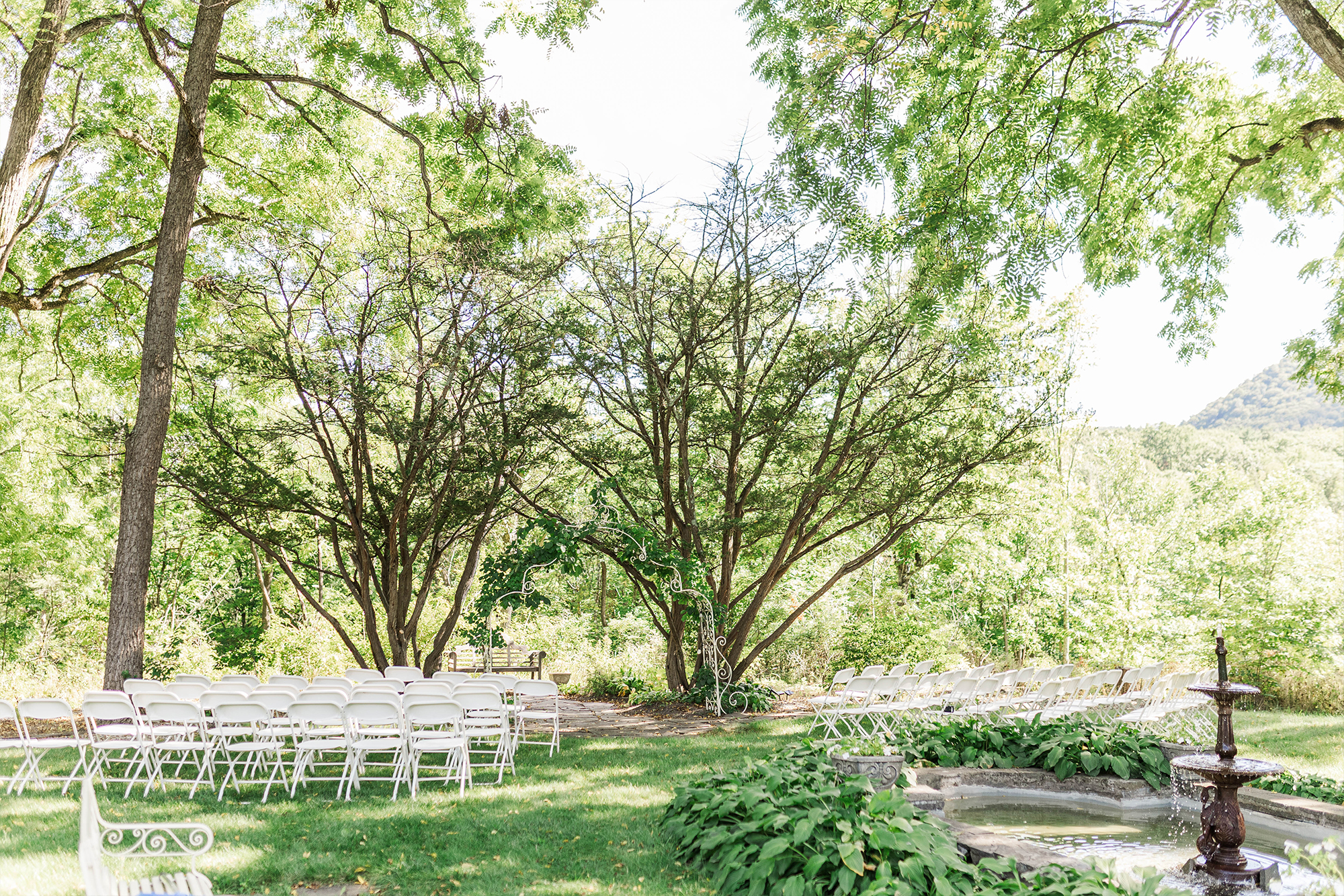 wedding ceremony space with arch, foldable chairs and fountain