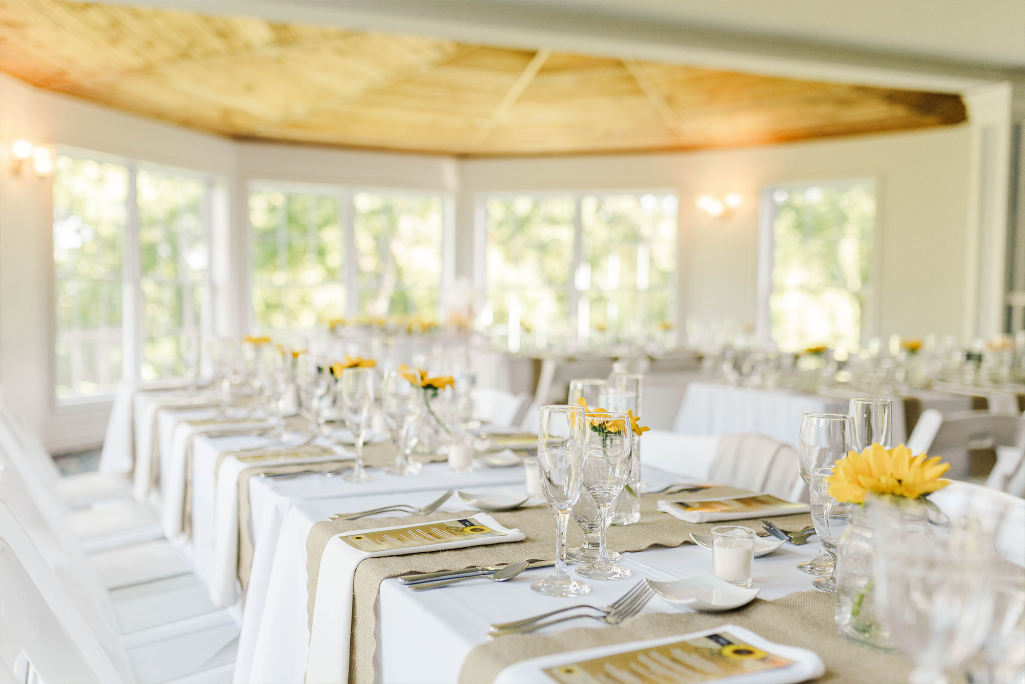 reception space with long tables, decorated with glassware, flowers, menus and cloths