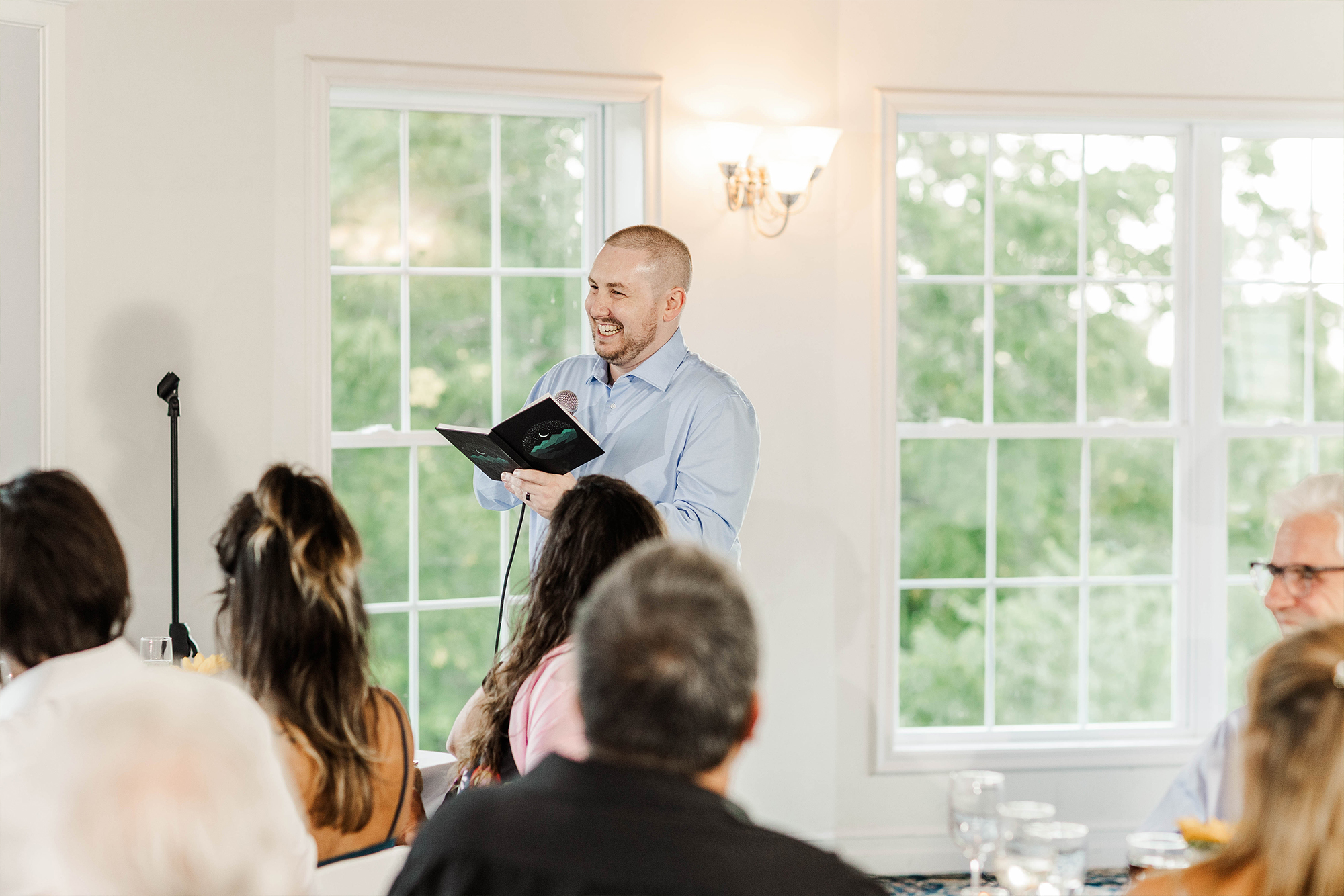 best man giving speech with notebook and microphone