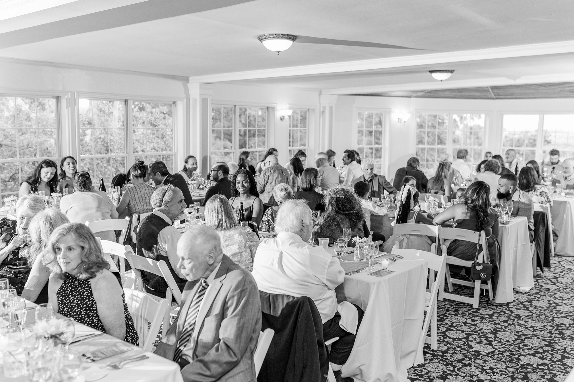 wide shot of reception space with guests seated at their tables making conversation