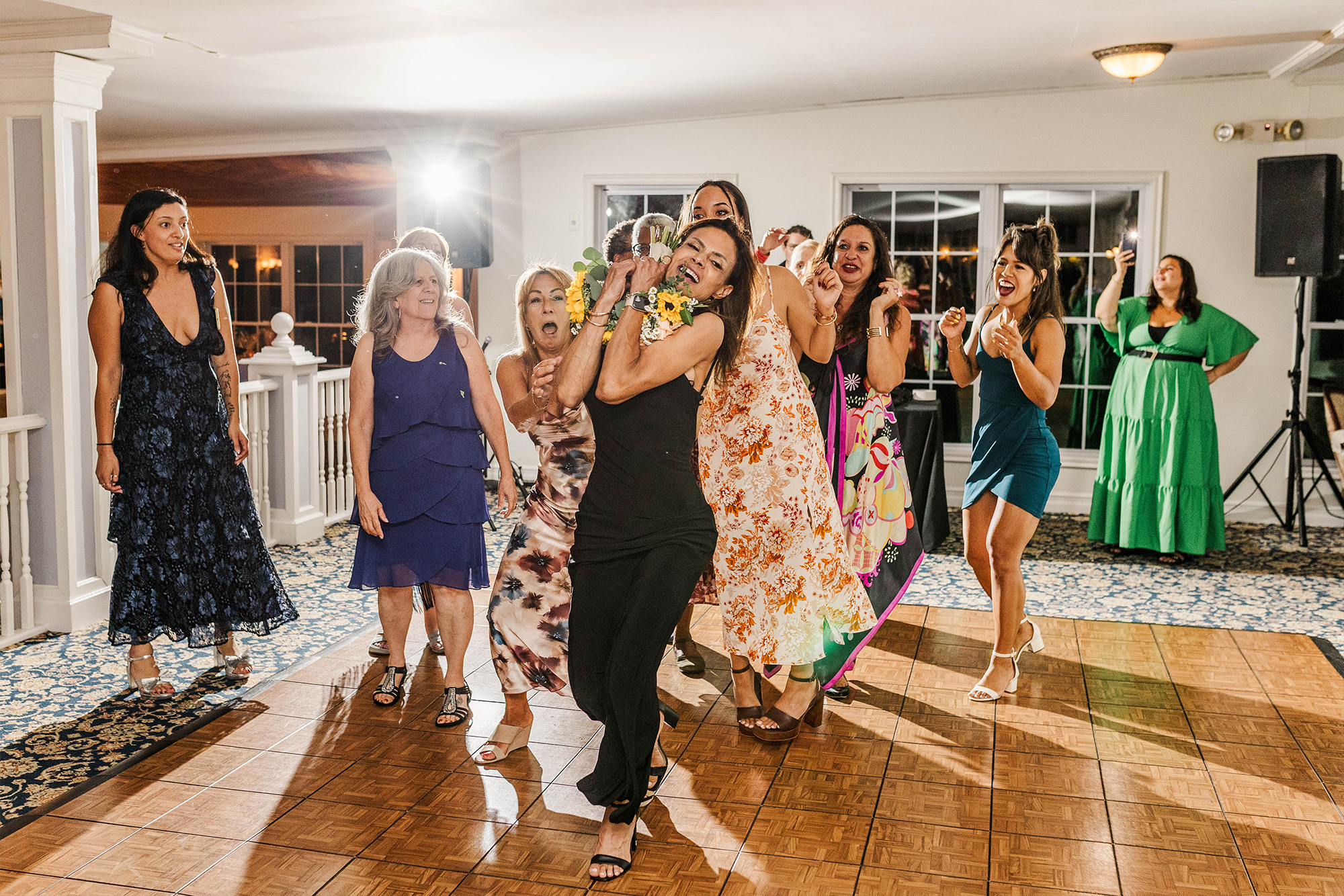 guest catches bridal bouquet surrounded by guests