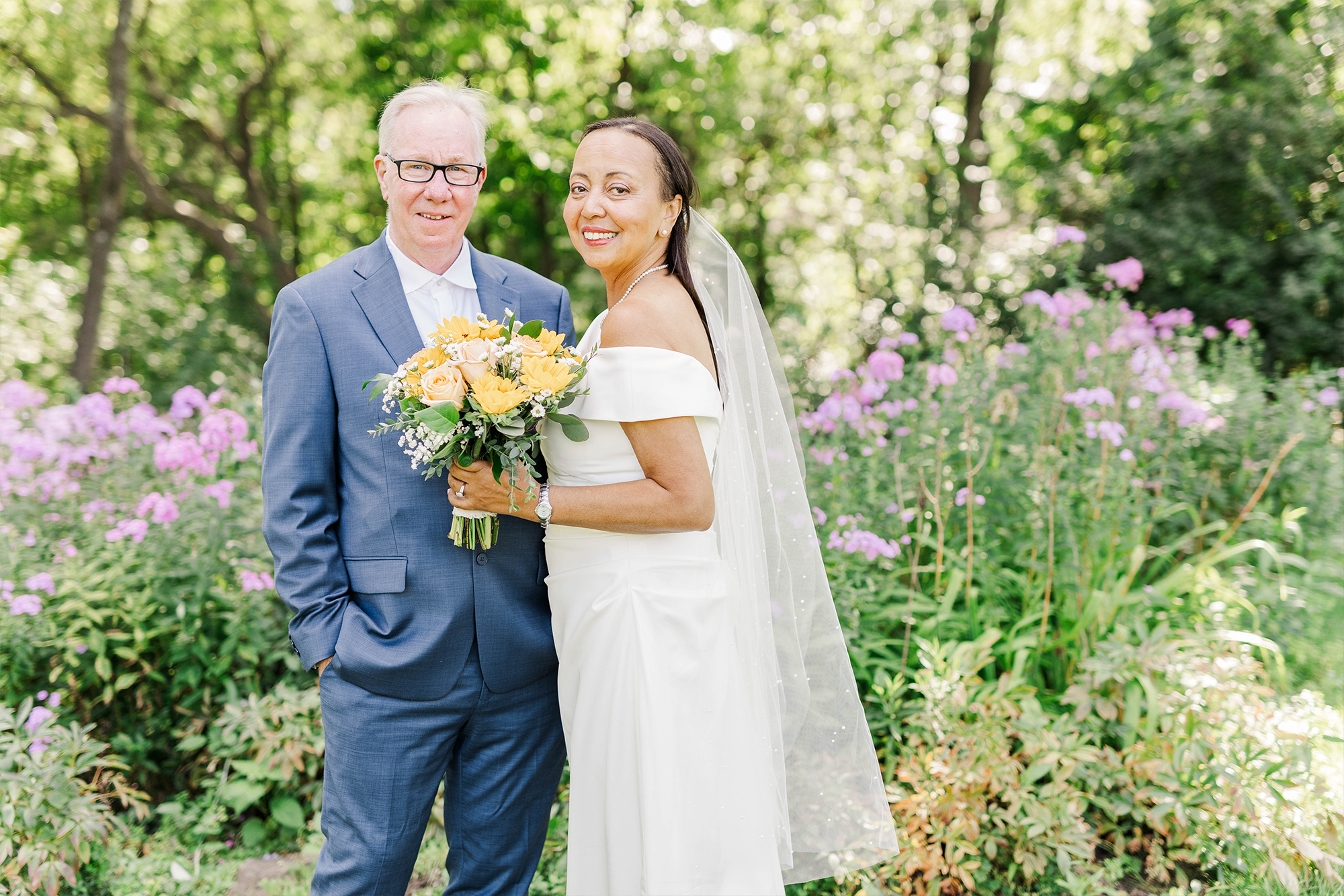 bride and groom posing with each other with bridal bouquet in greenery